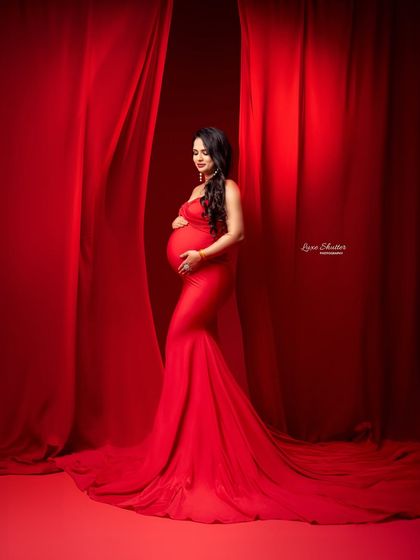 This pose, with the mother-to-be gently holding her bump, is a classic for a reason. It’s a beautiful expression of love and connection, amplified by the bold red setting.