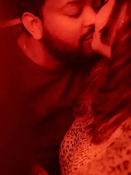 An artistic and passionate close-up, viewed through a red-tinted frame. The image captures a kiss, with the intense color and tight crop adding to the scene's drama and emotion.