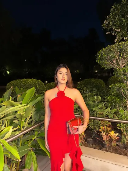 A full-length shot of the red dress, holding a matching red clutch. The perfect prom or date night look.