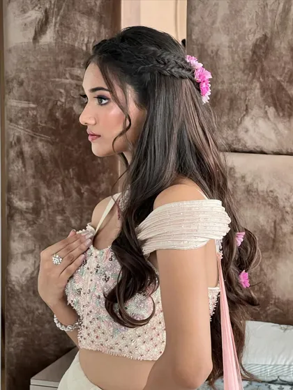 A beautiful profile shot of the client with her floral half-updo, showcasing how the style complements her off-shoulder blouse.