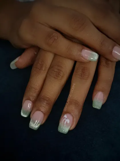 A soft green cat-eye French tip with a small, delicate bow accent. This is a subtle way to wear the cat-eye trend.