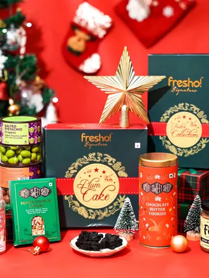 A close-up of a Fresho! Signature Christmas hamper, highlighting the festive packaging and variety of products. The warm lighting and holiday decor create an inviting gift-giving scene.