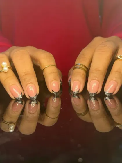 A unique take on the French manicure with jagged, sparkling black glitter tips on a sheer pink base.