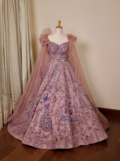 Isn't this the dreamiest gown ever? This lilac creation with peacock embroidery and dramatic cape sleeves is a true work of art, available to rent or buy.