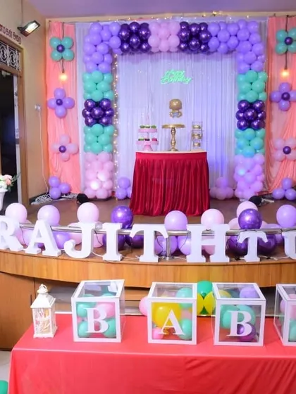 A sweet and simple first birthday setup in pastel purple, pink, and mint green. The column-style balloon arch and "BABY" blocks create a lovely backdrop for a smaller celebration.