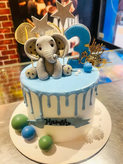 A blue drip cake topped with an adorable fondant elephant for a 3rd birthday.