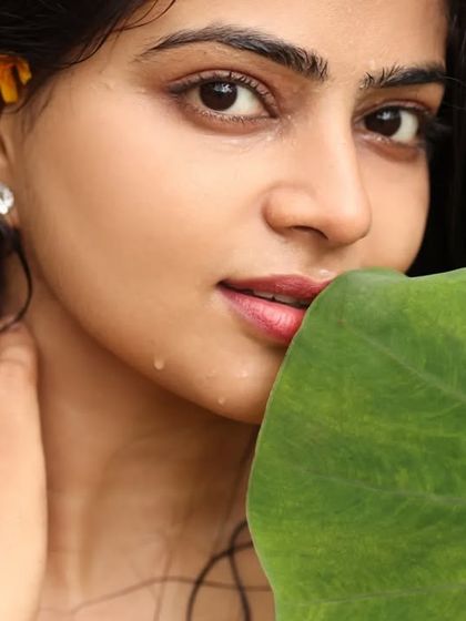 A simple, natural light portrait of a model. The close-up framing and the use of a leaf to partially frame the face create an intimate and organic feel.