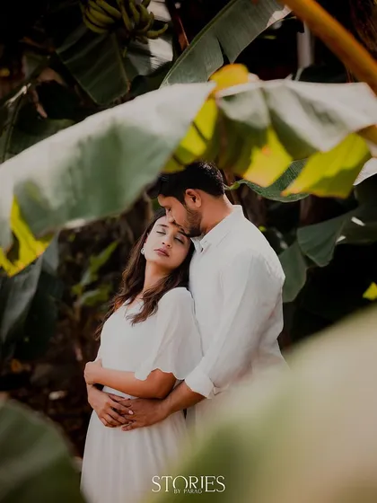 Framed by lush banana leaves, this couple shares a serene embrace. The all-white outfits create a beautiful contrast with the vibrant green, resulting in a pure and timeless portrait.