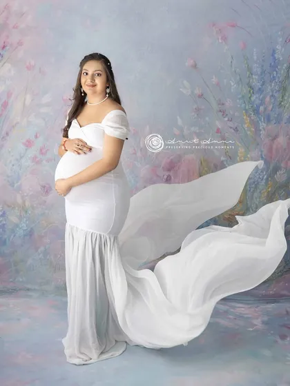 The flowing train of the white gown creates a sense of movement and grace in this elegant solo portrait, making the mother to be look truly radiant.