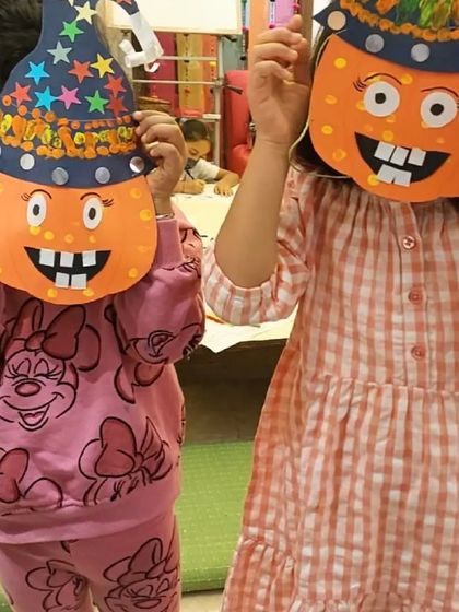 Getting into the Halloween spirit with some spooky fun. Two of our students hide behind the pumpkin masks they created during our themed workshop.