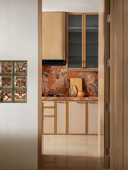 Another perspective of the kitchen entrance, highlighting the beautiful contrast between the red marble and the light wood cabinets.