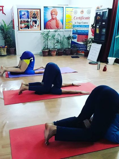 Students in Karnapidasana (Ear Pressure Pose), a deep forward-bending inversion. This advanced asana brings a profound sense of calm and introspection, blocking out external sounds.