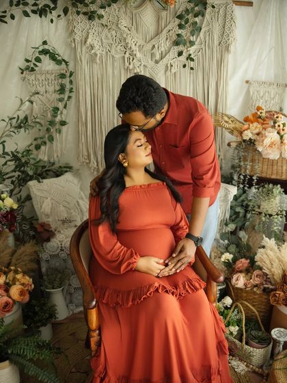 A tender moment between a couple, with a loving kiss on the forehead. Their coordinated rust-colored outfits create a harmonious and warm visual.