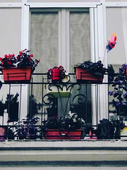 A classic European-style window balcony. We use railing planters filled with colorful flowers to add charm and curb appeal to your home's exterior.