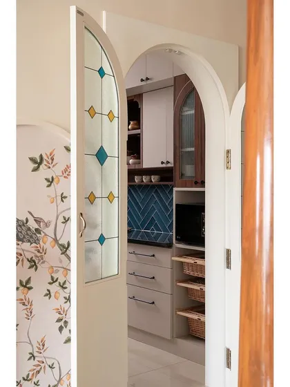 The stained glass kitchen door, seen here slightly ajar, offers a peek into the contemporary kitchen while maintaining the traditional feel of the living and dining areas.