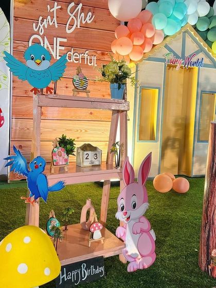 Adorable details from the enchanted forest theme, including rabbit and bird cutouts, a miniature shelf with props, and a sign that reads "Isn't she ONEderful".