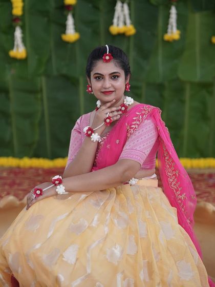 A portrait of the bride at her Haldi function, showcasing the fresh floral jewelry and the simple, elegant backdrop of banana leaves and marigolds.