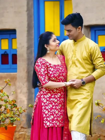 A sweet moment from a village-themed pre-wedding shoot. The colorful backdrop and traditional outfits create a charming and unique visual story.