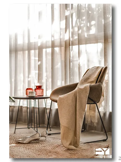 A quiet reading corner bathed in soft, diffused light from a large window. A comfortable chair, a warm throw, and a small side table create an intimate and peaceful spot for relaxation.