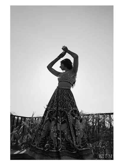 A bride's silhouette against the bright sky. This artistic, black and white shot focuses on her form and the intricate details of her lehenga, creating a timeless and elegant portrait.