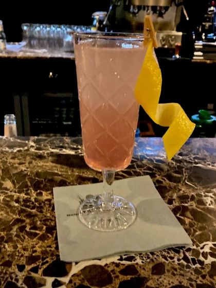 An elegant pink cocktail served in a vintage-style glass. The simple yet beautiful lemon peel twist garnish adds a touch of class.