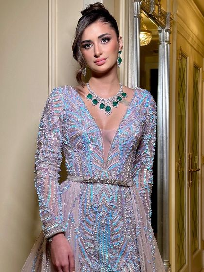 A vision in pastels and emeralds. This high-glam evening look features a flawless base and a soft smoky eye, allowing the iridescent gown and statement jewelry to shine.