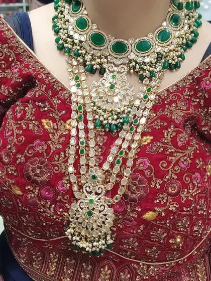 A bride looking absolutely regal in a layered green kundan and polki set, featuring a choker and a long multi-strand haar.