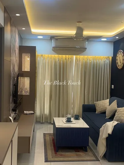 A full view of the living room with its deep blue sofa and warm cove lighting. The layout is designed to maximize comfort and create a welcoming environment for family and guests.