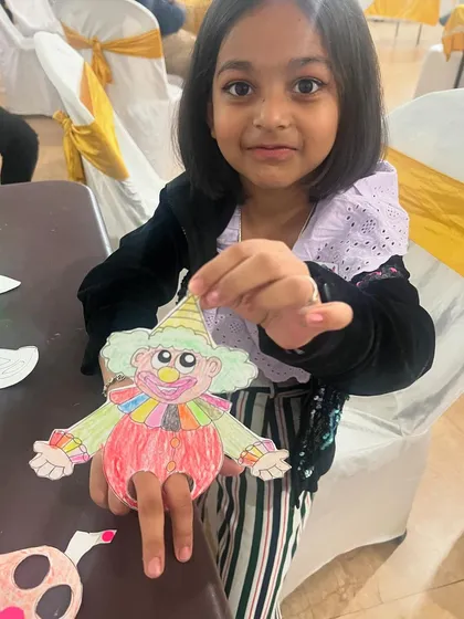 A young artist proudly displays the clown finger puppet she created. Our craft activities are designed to be fun for a wide range of ages.
