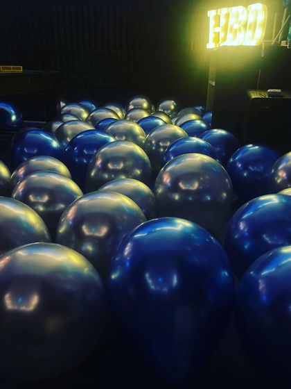 A close-up of the metallic blue and silver balloons covering the floor, adding to the immersive party feel.