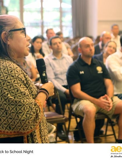 A parent asks a question during a presentation. We encourage open dialogue and value the perspectives of our families.