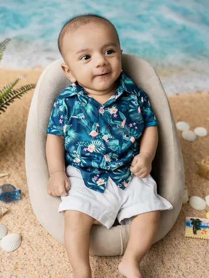 A sweet, content expression. Even without the sunglasses, his charm shines through in this tropical-themed baby photoshoot.