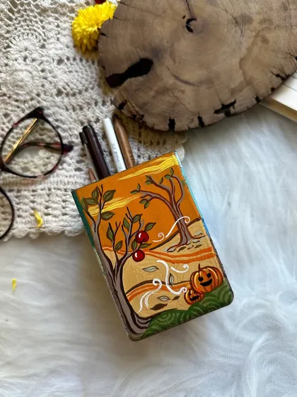 A four-seasons themed pen stand, with each side representing a different time of year. This side shows a cozy autumn scene.