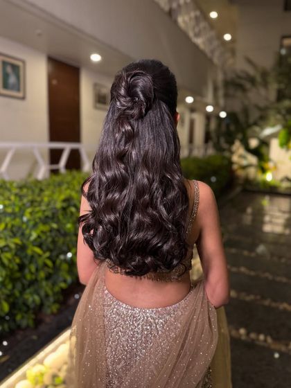 A look that is both chic and clean. This hairstyle, a half-up knot with loose waves, is perfect for a cocktail or sangeet event.