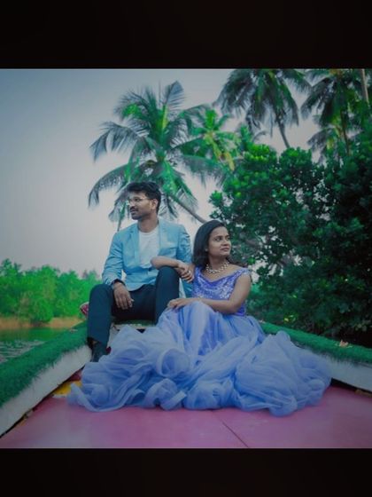 A cinematic shot of a couple on a boat, looking out at the scenery. The flowing lavender-blue gown adds to the dreamy, romantic feel.