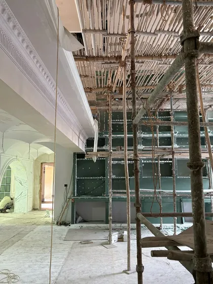 A side view of the interior construction, showing the framework for built-in shelving and the intricate ceiling details beginning to take shape.