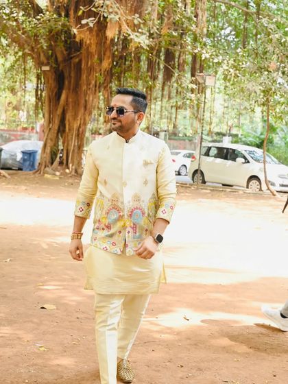 This ivory-colored kurta is paired with a unique jacket made from organza fabric. The jacket features colorful, abstract embroidery, making it a standout piece for a Sangeet.