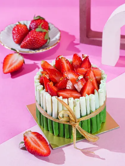 This strawberry cake is styled with a fresh, modern aesthetic. We used a two-toned pink background and geometric props to create a contemporary feel, while the gold ribbon adds a touch of elegance.