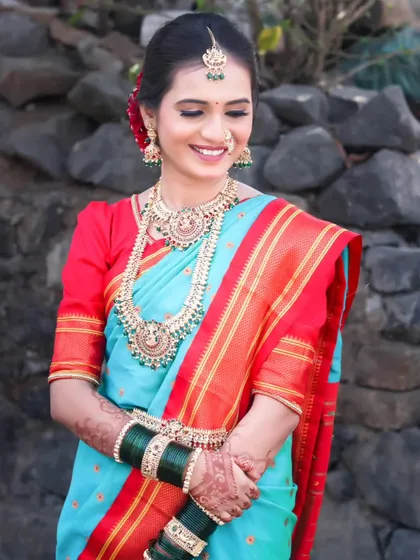 A classic bridal portrait featuring a beautiful bride in a traditional sky-blue and red Paithani saree. The focus is on her serene expression and the rich details of her attire.