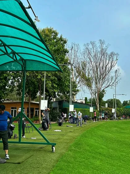 A wide view of the driving range, showing the portable covered bays and the expansive green.