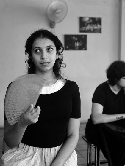An actor uses a fan to cool down during a break in rehearsals.
