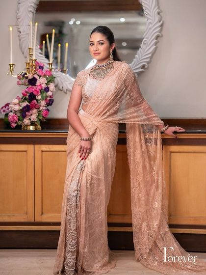 A full-length portrait showcasing the exquisite lace and embroidery of the designer saree.