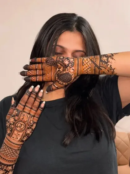 A client playfully hiding her face behind her beautifully done hands. It's all about having fun with your mehndi.