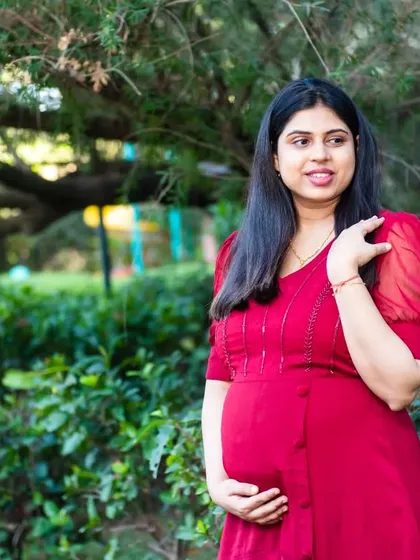A beautiful solo shot of the mom-to-be in a simple red dress, enjoying a quiet moment in the park.