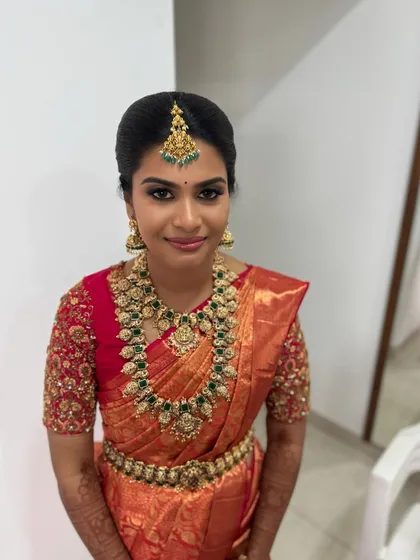 A classic portrait of Abi, looking confident and beautiful. Her makeup is flawlessly applied to enhance her features and complement her stunning red and gold bridal saree.