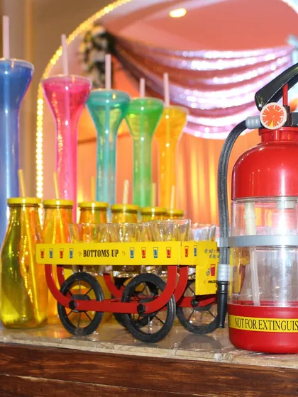 No party is complete without some fun. Here we have a selection of quirky drinkware, including colorful yard glasses, a fire extinguisher dispenser, and a miniature cart for serving shots, all designed to get the party started.