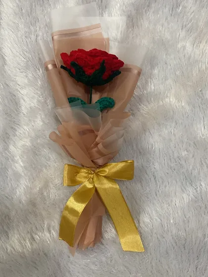 Another angle of the single red rose, showing the layers of wrapping paper and the elegant gold bow.