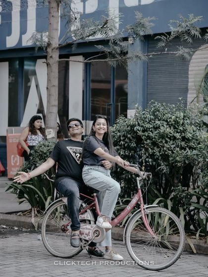 A fun and quirky pose on a tandem bicycle, capturing the couple's playful side in a city setting.