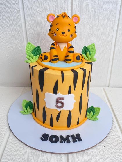 A roaringly cute tiger-themed cake for a fifth birthday. The cake features tiger-stripe patterns and is topped with a sweet, hand-sculpted tiger cub.