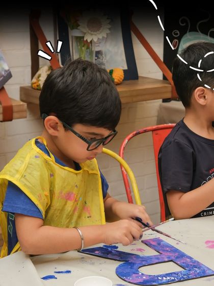 A child carefully works on painting a large letter 'B', showing intense focus. Activities like this help improve fine motor skills while being incredibly fun.
